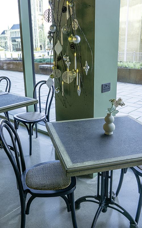 Hands opening a champagne bottle during a casual outdoor dining experience with friends.